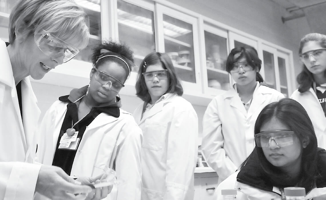 Group of women wearing lab coats performing an experiment