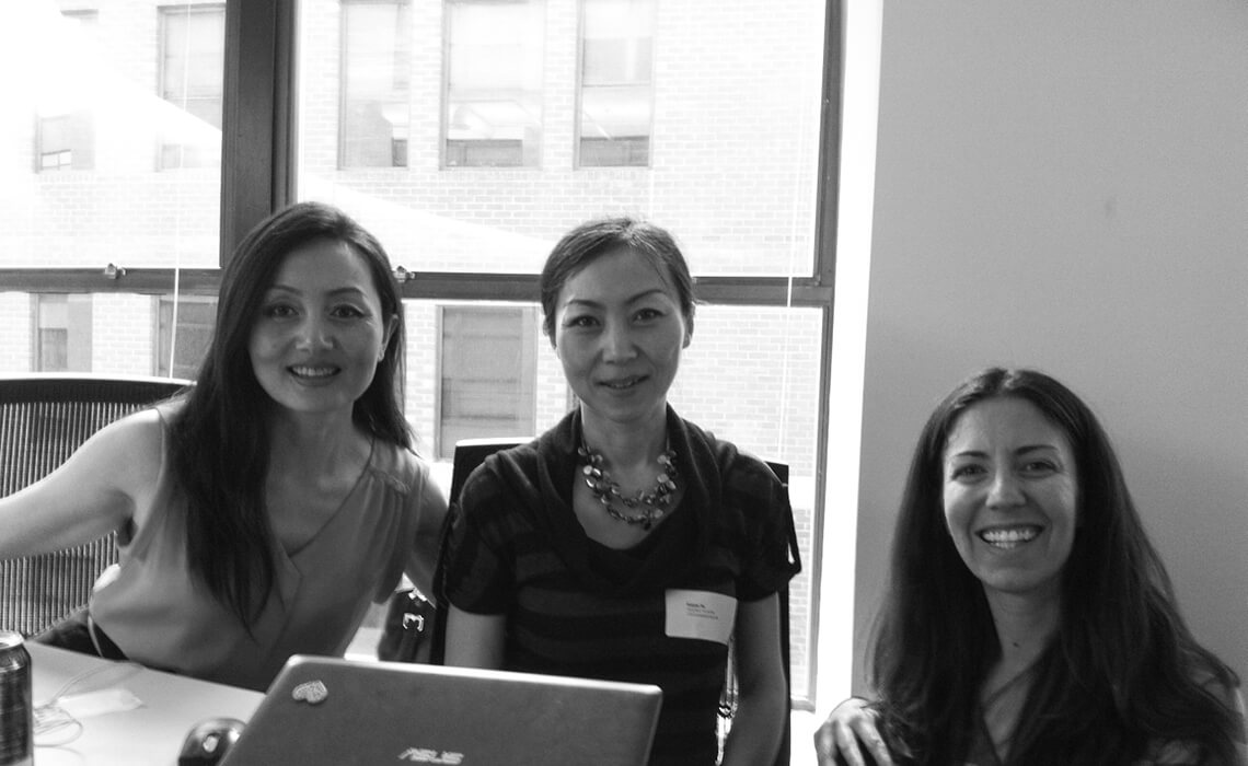 Three women sitting in front of laptop smiling at the camera