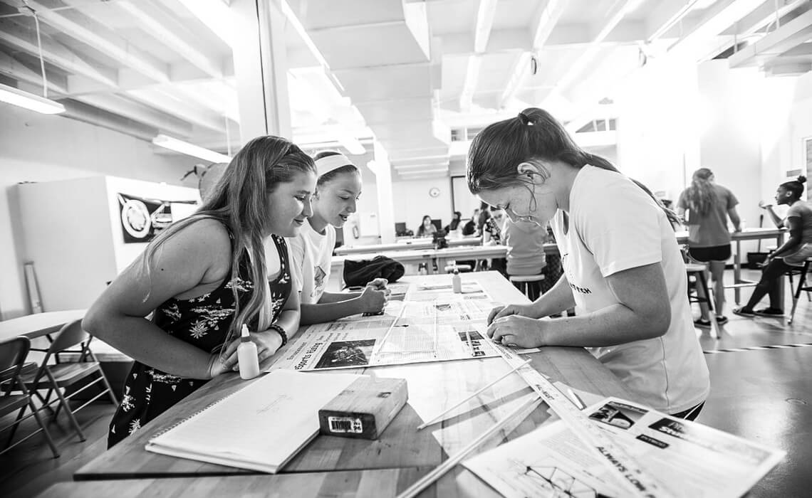 Three women around at a table working on a project together